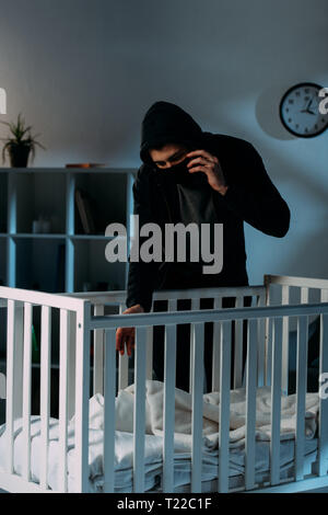 Criminal in mask talking on smartphone while kidnapping child Stock Photo