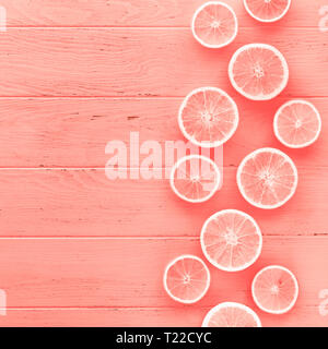 Creative scandinavian style flat lay top view of fresh orange fruit slices on coral wooden table background with copy space. Minimal summer fresh citr Stock Photo