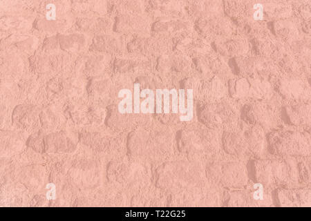 Old vintage cobble stone street background texture toned in trend color Living Coral. Stock Photo