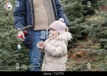 Happy girl with father decorating Christmas tree on a plantation Stock Photo