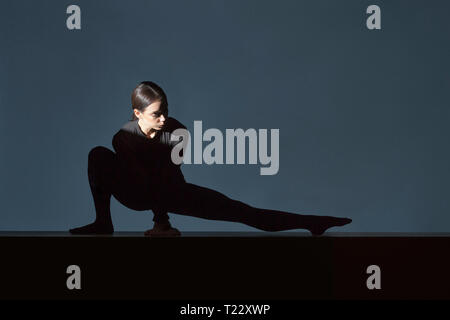 Woman dressed in black doing stretching exercise Stock Photo