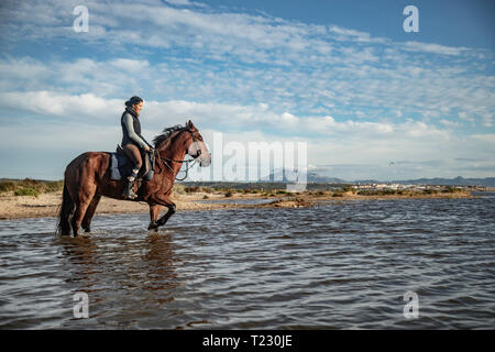 Spain, Tarifa, woman riding horse on the beach at sunset Stock Photo ...