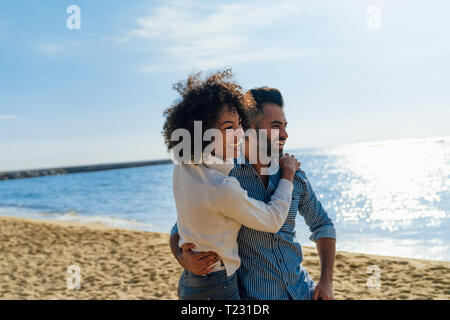 Spain, Barcelona, happy couple hugging on the beach Stock Photo