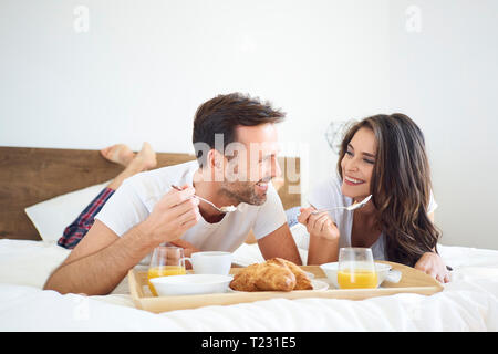 Happy couple having breakfast in bed Stock Photo