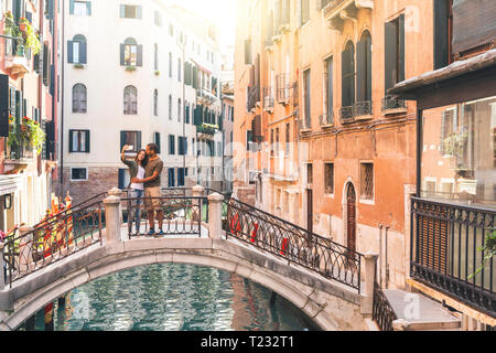 Italy, Venice, young couple standing on a small bridge taking a selfie Stock Photo
