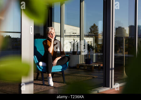 Woman sitting in armchair with closed eyes Stock Photo