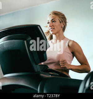 Young woman jogging on treadmill. Selective focus, toned image. Stock Photo