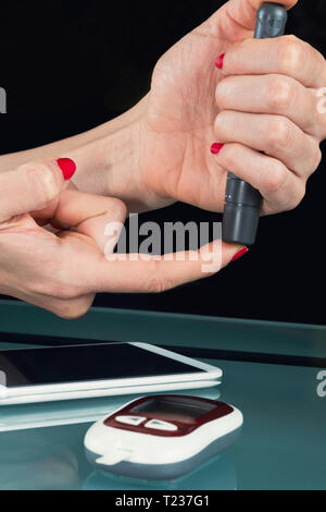 Using blood sugar testing lancet on finger. Stock Photo