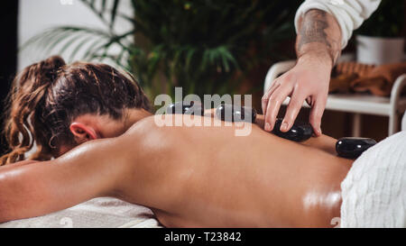 Young woman having hot stone massage. Stock Photo