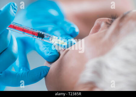 Hyaluronic acid injections. Mature woman receives hyaluronic acid injections for reducing cheek wrinkles. Anti-aging concept. Stock Photo