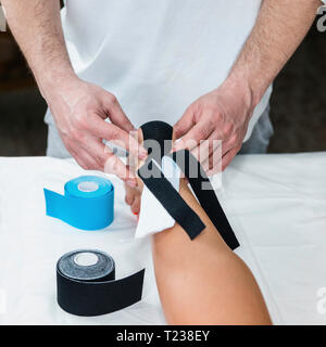 Physical therapist placing tape on patient's heel. Stock Photo
