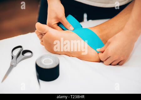 Physical therapist placing kinesio tape on patient's foot. Stock Photo