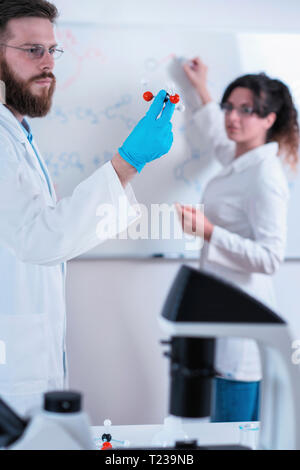 Young researchers working together in the lab wearing uniform. Stock Photo