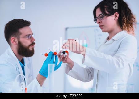 Young students researching together in the lab, wearing safety glasses and gloves. Stock Photo