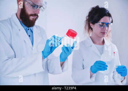 Young researchers working together in the lab, wearing uniform. Stock Photo