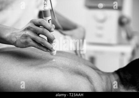 Therapeutic laser technology. Therapist using medical laser beam on a patient's back. Stock Photo