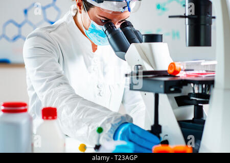 Scientist working in a laboratory, placing microscope slide on the stage. Stock Photo
