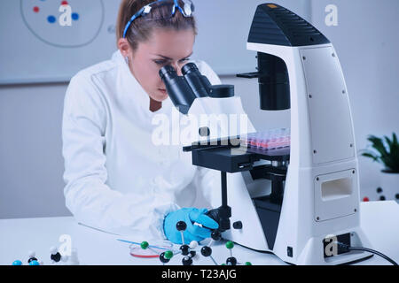 Female scientist looking through the microscope. Stock Photo