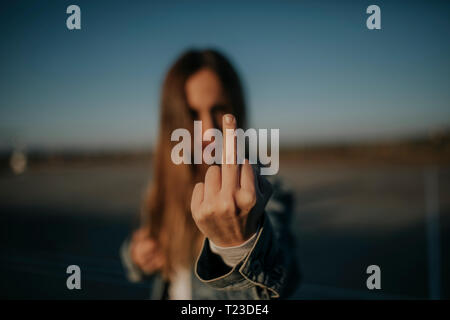 Close-up of young woman outdoors giving the finger Stock Photo