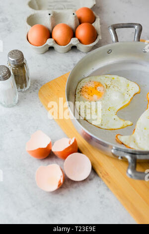 Eggs in a box, fried eggs in pan and eggshells Stock Photo