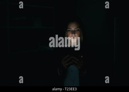 Young woman using digital tablet in he dark Stock Photo