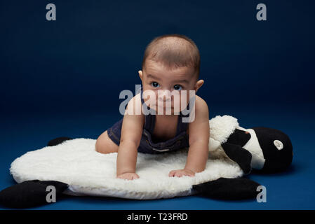 Looking on side baby boy in blue studio background Stock Photo