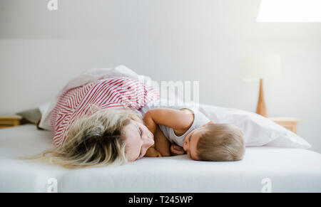 Mother and toddler son lying in bed at home Stock Photo