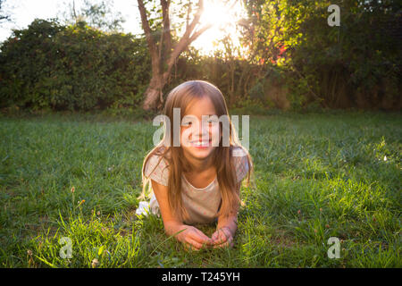 Portrait of a smiling little girl, lying on green grass Stock Photo - Alamy
