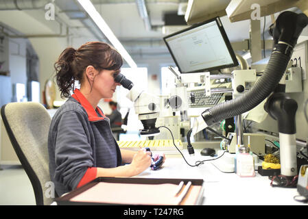 Woman using a microscope for the quality control in the manufacturing of circuit boards for the electronics industry Stock Photo