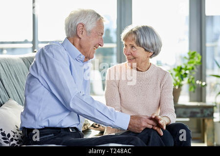 Senior couple sitting on couch talking together Stock Photo