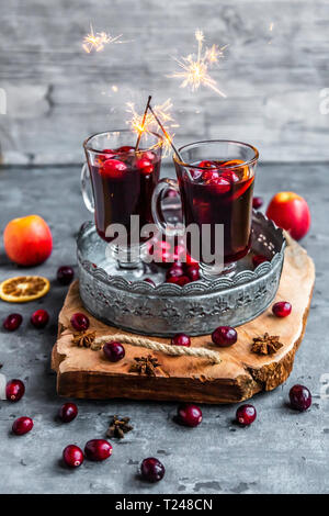Two glasses of Mulled Wine with cranberries, orange slices and star anise with sparklers Stock Photo