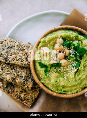 Peas hummus in wooden bowl, crispbread on plate Stock Photo
