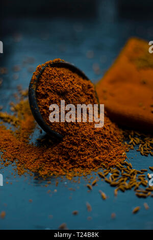 Close up of powdered cumin or zeera or jeera with raw cumin on wooden surface in a clay bowl on a cloth or napkin. Stock Photo