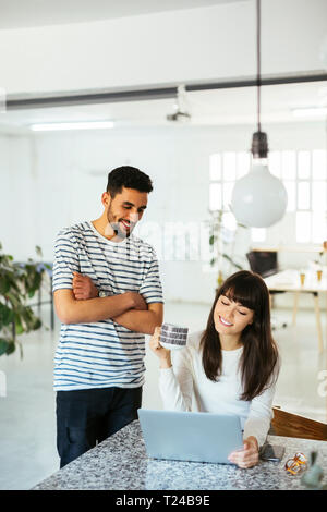 Two smiling colleagues working together at table with laptop Stock Photo