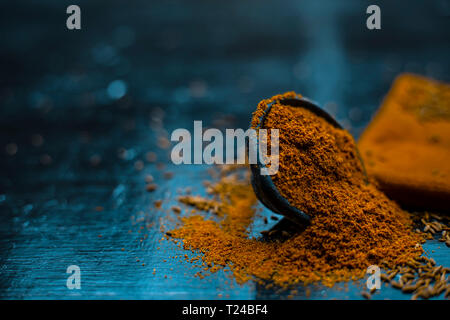 Close up of powdered cumin or zeera or jeera with raw cumin on wooden surface in a clay bowl on a cloth or napkin. Stock Photo