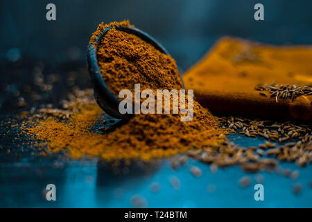 Close up of powdered cumin or zeera or jeera with raw cumin on wooden surface in a clay bowl on a cloth or napkin. Stock Photo