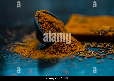 Close up of powdered cumin or zeera or jeera with raw cumin on wooden surface in a clay bowl on a cloth or napkin. Stock Photo