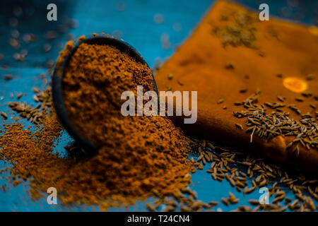 Close up of powdered cumin or zeera or jeera with raw cumin on wooden surface in a clay bowl on a cloth or napkin. Stock Photo