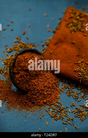 Close up of powdered cumin or zeera or jeera with raw cumin on wooden surface in a clay bowl on a cloth or napkin. Stock Photo