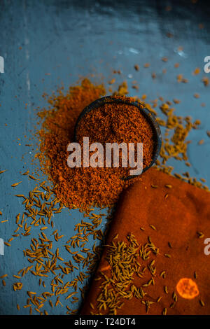 Close up of powdered cumin or zeera or jeera with raw cumin on wooden surface in a clay bowl on a cloth or napkin. Stock Photo