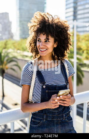 Young woman standing on a bridge, using smartphone Stock Photo