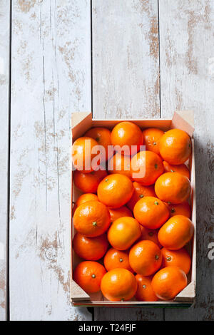 Tangerines in crate, on white, wooden background Stock Photo