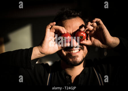 Man covering his eyes with tomatoes Stock Photo