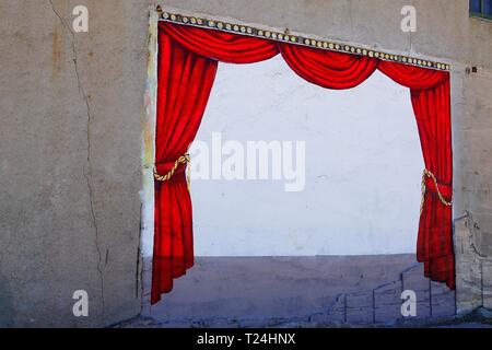 A mural of a stage with a red curtain is painted on the side of a wall ready for a performance in the small town of Miami, Arizona. Stock Photo
