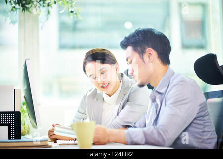 asian business man and woman working together in office using tablet PC. Stock Photo