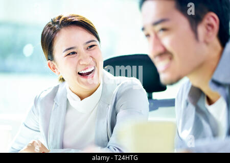 asian businesswoman laughing during meeting with male colleague in office. Stock Photo