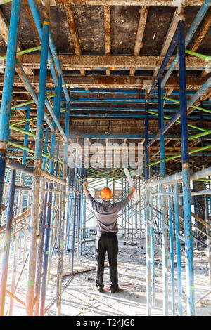 Engineer or foreman with blueprint in building construction site. He push his hands up to success on building construction site. Stock Photo