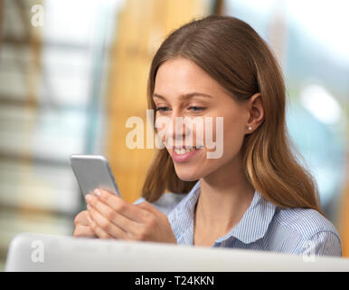Smiling businesswoman using cell phone in office Stock Photo