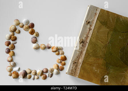 Vacation diary lying next to summer-like heart made from seashells creating a vacation vibes arrangement. Stock Photo