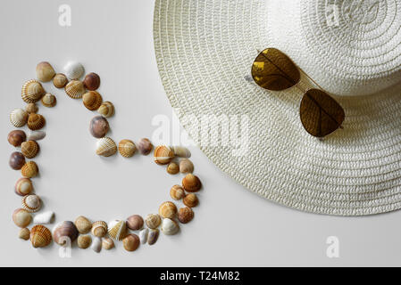 Summer fashion arrangement made from summer straw hat, aviator sunglasses and seashells from beach resort. Stock Photo